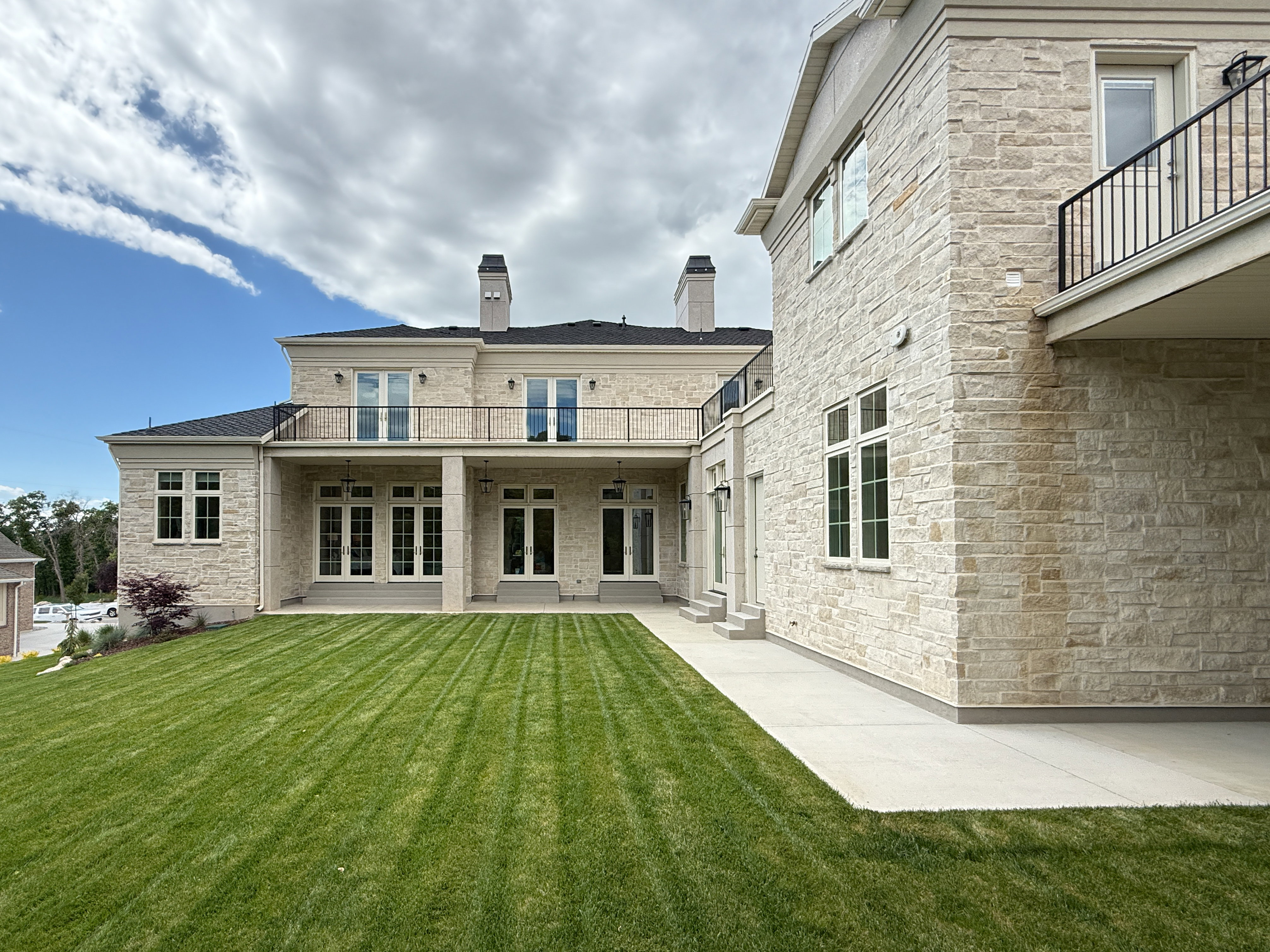 Rear view of property with a balcony, french doors, a yard, a patio area, and a chimney
