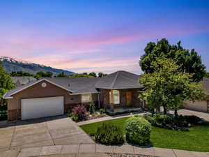 Ranch-style home with brick siding, driveway, a garage, a front lawn, and a mountain view