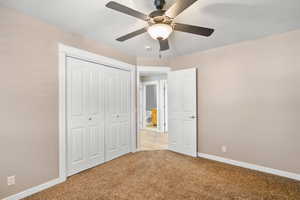 Unfurnished bedroom with carpet, baseboards, a closet, and ceiling fan