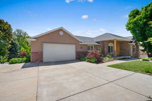 Ranch-style home featuring brick siding, a garage, driveway, and roof with shingles