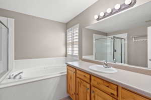 Bathroom with a stall shower, a bath, and vanity