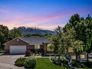 View of front of house featuring brick siding, concrete driveway, an attached garage, a mountain view, and stone siding