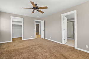 Unfurnished bedroom featuring light colored carpet, a walk in closet, baseboards, and ensuite bathroom