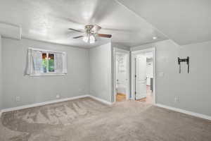 Unfurnished bedroom with carpet floors, a textured ceiling, baseboards, connected bathroom, and a ceiling fan