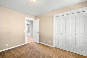 Unfurnished bedroom featuring carpet, baseboards, and a closet