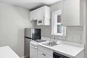 Kitchen featuring white appliances, a sink, and white cabinetry
