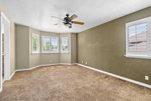 Carpeted empty room featuring ceiling fan and baseboards