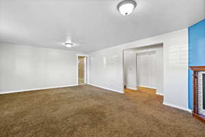 Spare room with carpet, a textured ceiling, baseboards, and a fireplace