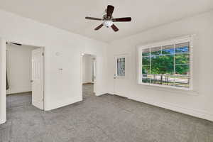 Carpeted empty room featuring ceiling fan and baseboards