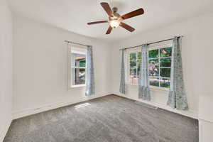 Carpeted empty room with a ceiling fan and baseboards