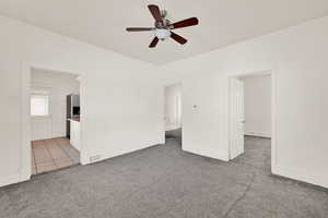 Carpeted spare room featuring ceiling fan and baseboards