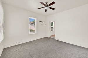 Empty room with carpet floors, a ceiling fan, and baseboards
