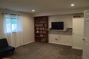Living area with dark colored carpet, recessed lighting, and baseboards