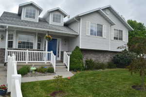 View of front of home featuring a porch, a front lawn, brick siding, and roof with shingles