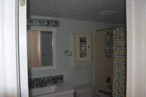 Full bathroom featuring vanity, toilet, a textured ceiling, and shower / bath combo with shower curtain