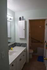 Full bathroom featuring toilet, vanity, a bath, a textured ceiling, and tasteful backsplash