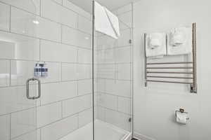 Full bathroom with radiator heating unit, a stall shower, and a towel warming rack