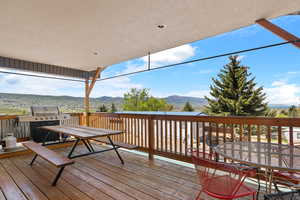 Deck with outdoor dining area, a mountain view, and grilling area Grill excluded