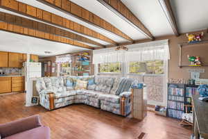 Living area featuring beam ceiling, plenty of natural light, and wood finished floors