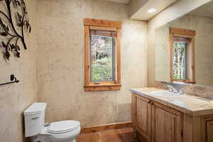 Bathroom featuring vanity, toilet, and baseboards