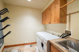 Laundry room with independent washer and dryer, baseboards, cabinet space, and light stone finish flooring