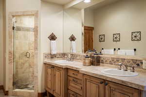 Bathroom featuring tasteful backsplash, double vanity, and a shower stall