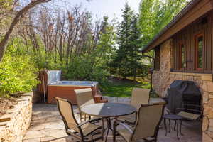View of patio / terrace with a hot tub, outdoor dining area, and a grill