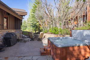 View of patio / terrace with a hot tub, grilling area, and outdoor dining space