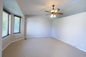 Carpeted spare room with a ceiling fan, baseboards, and vaulted ceiling
