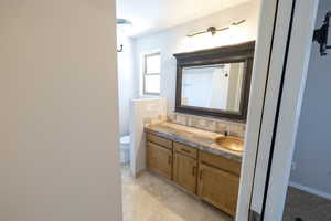 Full bath with vanity, toilet, decorative backsplash, baseboards, and a shower with curtain