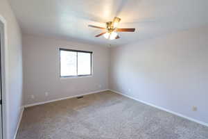 Carpeted spare room with ceiling fan, baseboards, and a textured ceiling