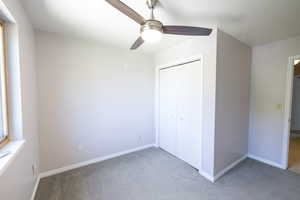 Unfurnished bedroom with light carpet, baseboards, a closet, and ceiling fan