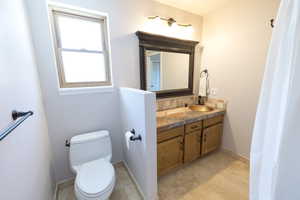 Full bath with vanity, toilet, decorative backsplash, and baseboards