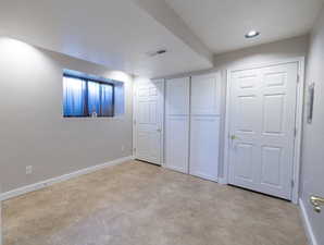 Basement featuring light carpet and baseboards