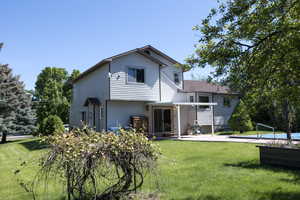 Back of property featuring a patio, a yard, and an outdoor pool