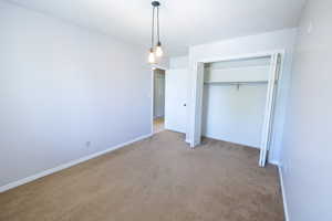 Unfurnished bedroom featuring carpet, a closet, and baseboards