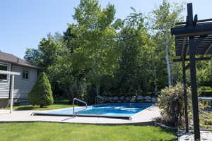 View of swimming pool featuring a covered pool and a yard