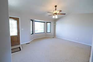 Entrance foyer featuring light carpet, a ceiling fan, baseboards, and vaulted ceiling