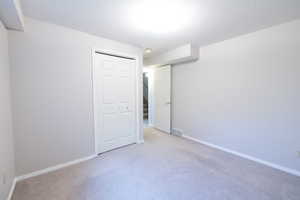 Unfurnished bedroom with light colored carpet, a closet, and baseboards