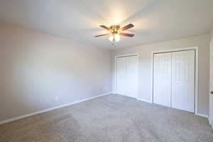 Unfurnished bedroom with multiple closets, carpet, baseboards, and a ceiling fan