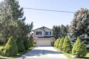 View of front of property featuring driveway, an attached garage, and brick siding