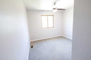 Carpeted empty room with a ceiling fan and baseboards