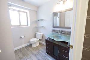 Bathroom featuring vanity, wood finished floors, toilet, and baseboards
