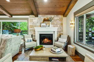Living area featuring wooden ceiling with exposed beams, wood finished floors, plenty of natural light, and a glass covered fireplace