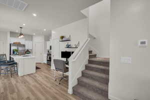 Living room featuring light wood-style floors, stairs, recessed lighting, and an office area