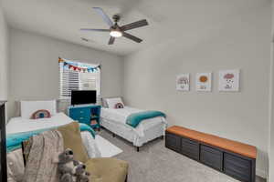 Carpeted bedroom with a ceiling fan
