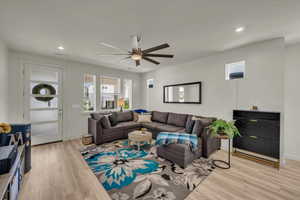 Living room with light wood-style flooring, a ceiling fan, recessed lighting, and baseboards
