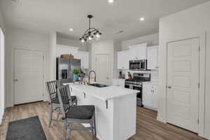 Kitchen with stainless steel appliances, a sink, tasteful backsplash, white cabinetry, and recessed lighting