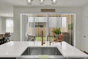 Kitchen with a sink, a kitchen island with sink, and light stone counters