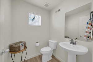 Bathroom featuring wood finished floors, toilet, and baseboards